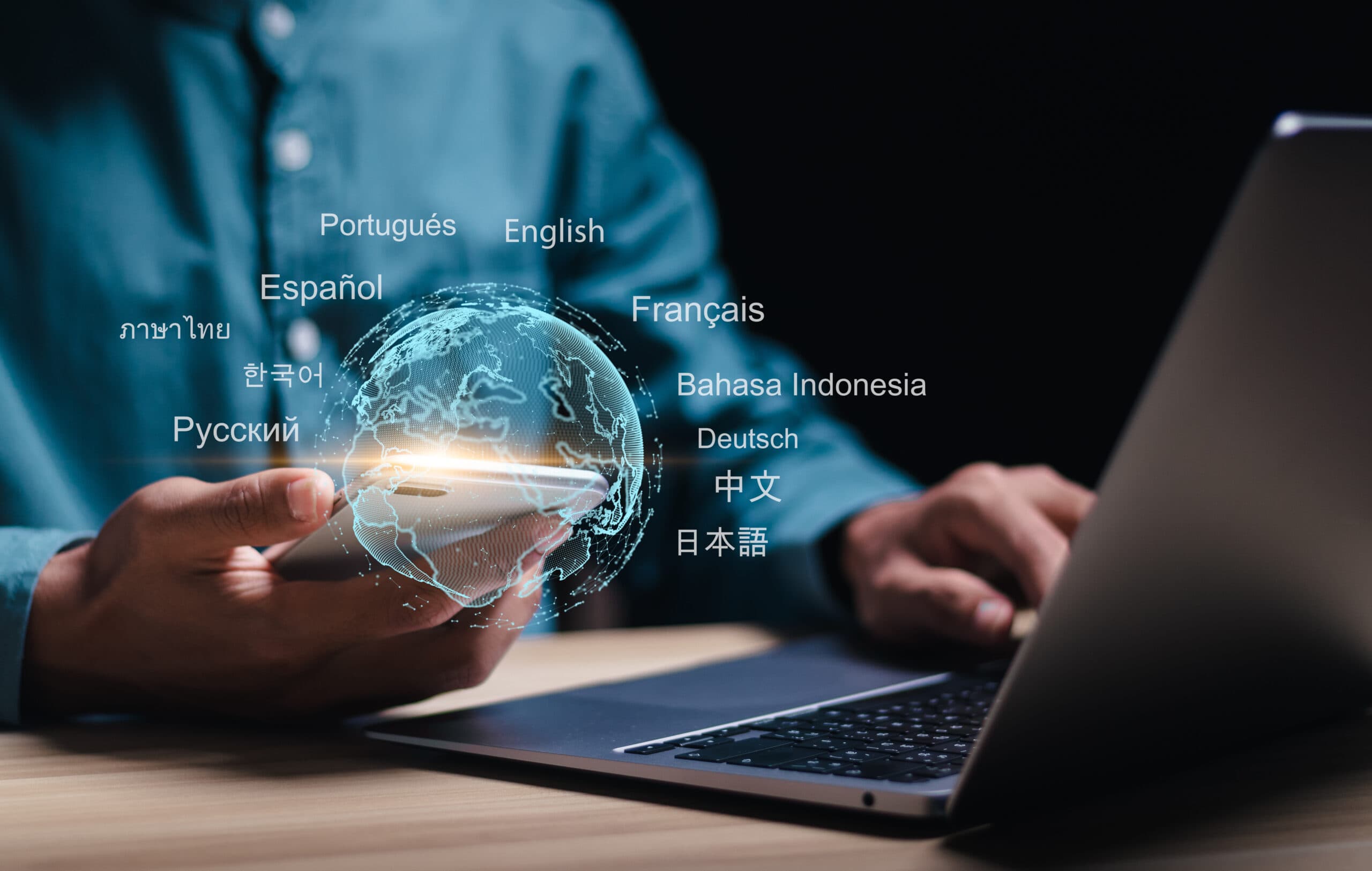 Man using his phone to translate while also looking at laptop.